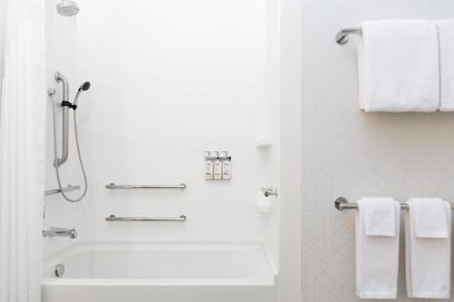 a white bathroom with a shower and a tub and towels at Candlewood Suites Anchorage - Midtown by IHG in Anchorage