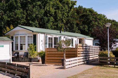 a small white house with a fence at Chalet aan de bosrand in De Koog
