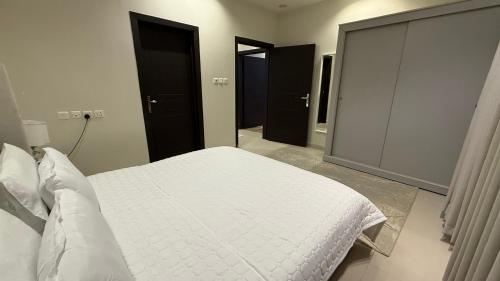 une chambre avec un lit blanc et des portes noires dans l'établissement شقق العارض (2), à Riyad