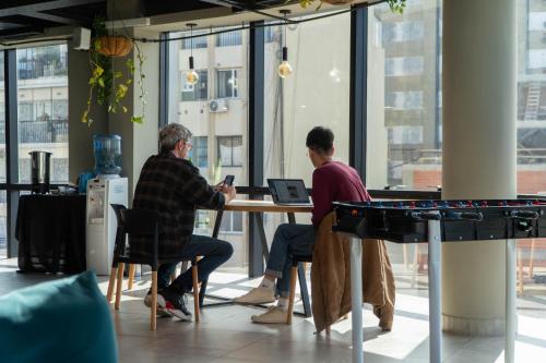 two men sitting at a table with a laptop at MONS hostel in Buenos Aires