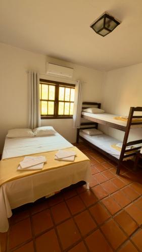 a bedroom with two beds and a window at Pousada Marina do Farol in São José da Barra