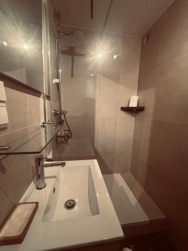 a white bathroom with a sink and a shower at Duin 10 in Katwijk aan Zee