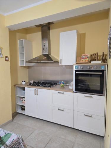 Una cocina con gabinetes blancos y un horno de estufa. en Villa Rosanna, en Caianello