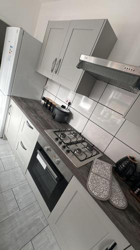 a kitchen with white cabinets and a stove top oven at City Escape Stylish 4 bedroom house in Nottingham Sleep 9 in Nottingham