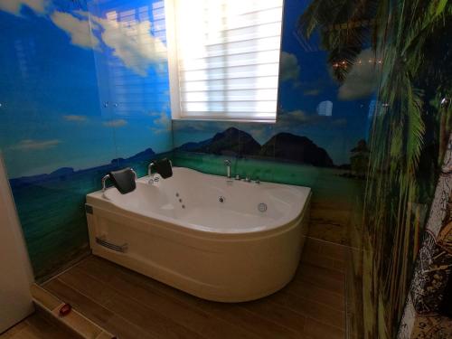 a bath tub in a bathroom with a mural at HOTEL St PAULI in Shkodër