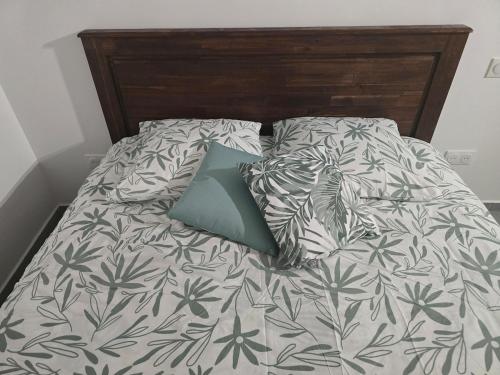 a bed with a gray and white comforter with a blue pillow at Le Cataleya in Sainte-Rose