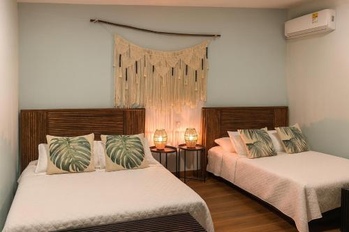 two beds in a room with two lamps and a window at Fragata Island House in Isla Grande