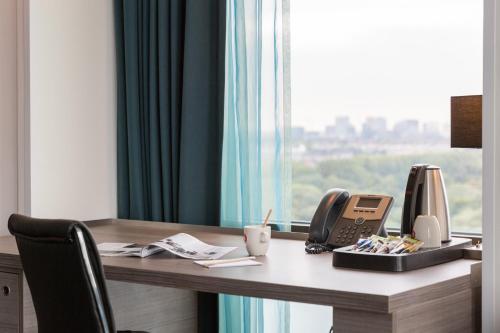 a room with a desk with a phone and a phone at Leonardo Hotel Amsterdam Rembrandtpark in Amsterdam