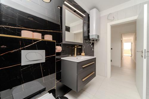a black and white bathroom with a sink and a mirror at Seaview Villa Summer with private pool & garden in Rtina
