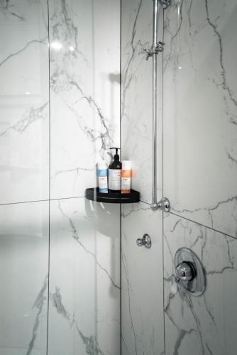 a bathroom with a shower with white marble walls at Princes Wharf - Spectacular Couple Getaway in Auckland