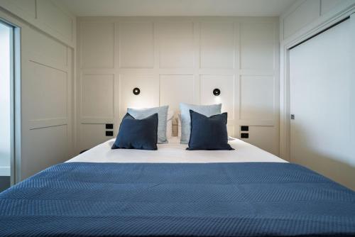 a bedroom with a large bed with blue pillows at Princes Wharf - Spectacular Couple Getaway in Auckland