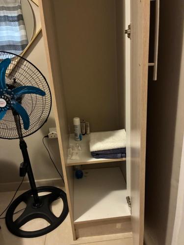 a room with a desk with a fan and a shelf at Horus Private Room in Gaborone