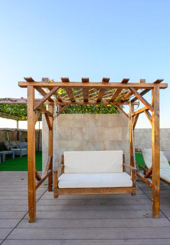 a wooden pergola with a white couch on a patio at Abraj INN Royal Hotel فندق أبراج إن الملكي in Doha