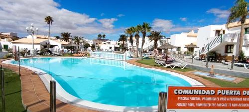 a large swimming pool in a resort with palm trees at Relax en Puerta del Sol - Caleta de Fuste in Caleta De Fuste