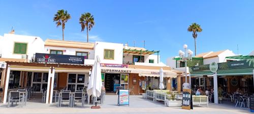 a group of shops on a street with palm trees at Relax en Puerta del Sol - Caleta de Fuste in Caleta De Fuste