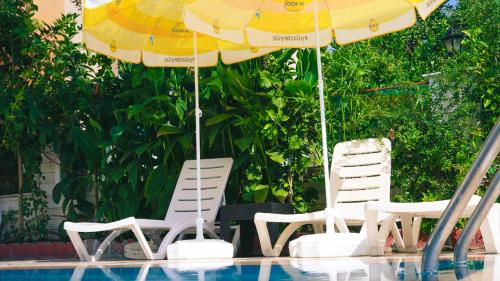 two chairs and an umbrella next to a swimming pool at MOY Beldibi Hotel in Antalya