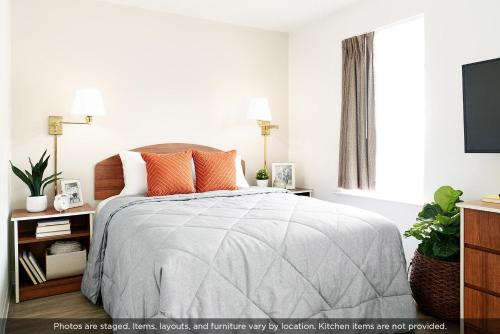 a bedroom with a bed with orange pillows at Intown Suites Extended Stay Warner Robins in Warner Robins