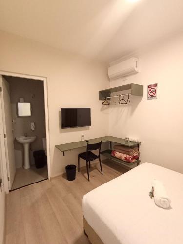 a room with two beds and a desk with a television at WeStay Nova Cidade in São Paulo