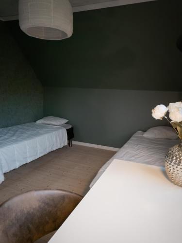 two beds in a room with green walls and a vase with flowers at Lakefront house on Skåne's largest island in Ivö