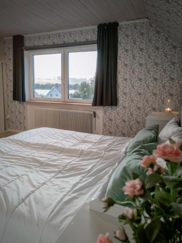 a bedroom with a bed with a window and flowers at Lakefront house on Skåne's largest island in Ivö