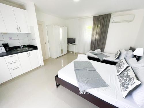 a white room with a bed and a kitchen at DELUXE HOTEL SUITES STUDIO del Mar Bavaro TROPICANA HOTEL WIFI Beach CLUB & SPA in Punta Cana