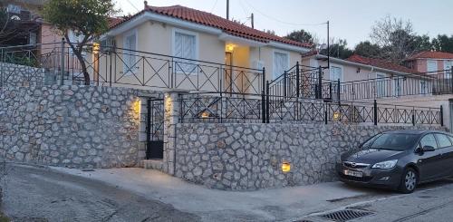 un'auto parcheggiata di fronte a un muro di pietra di Eugenies Home a Áno Váltai