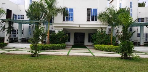 a white building with palm trees in front of it at Park Springs Hotel in Cape Coast