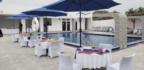 a group of tables and umbrellas next to a pool at Park Springs Hotel in Cape Coast