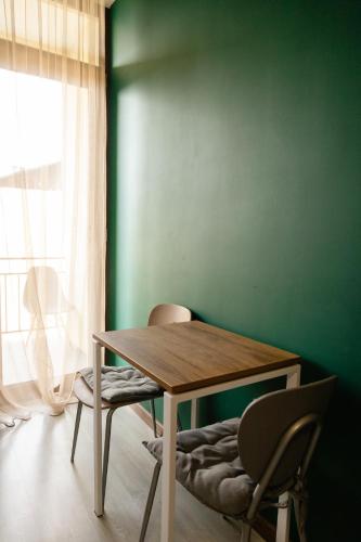 a table and chairs in a room with a green wall at Hotel Graif Ti in Tbilisi City