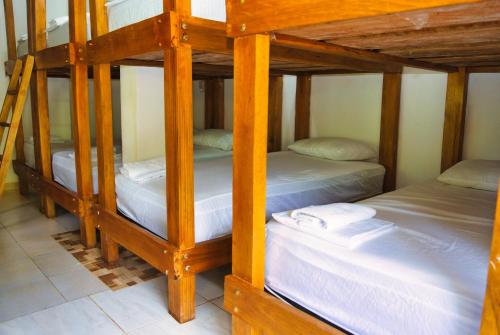 a room with three bunk beds with white sheets at Hostal Sierra Quindío in El Fénix
