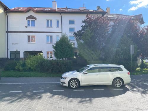 a white car parked in a parking lot in front of a building at Apartament Przystań w Ustce - 120 m2 - 200 m od plaży Mickiewicza 2 in Ustka