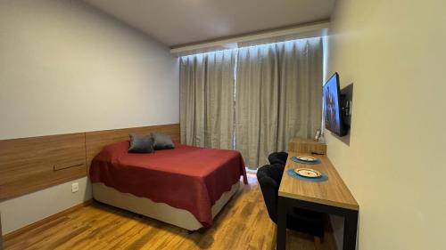 a bedroom with a bed and a desk with a television at Loft Sofisticado no Bairro Alto - Teresópolis in Teresópolis