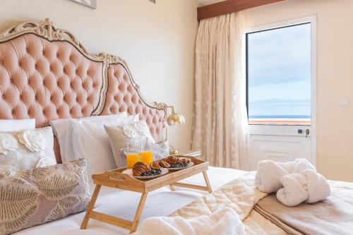 een slaapkamer met een groot roze bed met een tafel met eten erop bij Villa Mar by Atlantic Holiday in Porto Moniz