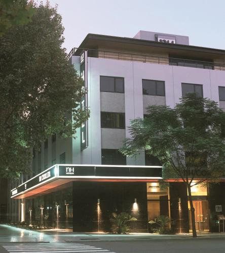 a large white building with a tree in front of it at NH Mendoza Cordillera in Mendoza