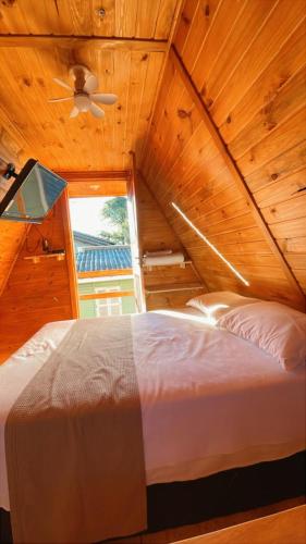 a bed in a wooden room with a ceiling at Cabanas da Faby in Canela