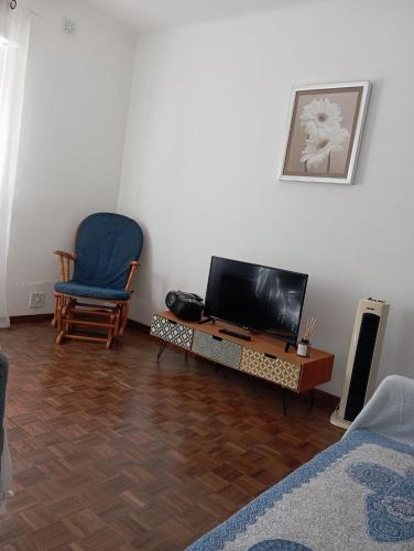 a living room with a tv and a blue chair at Villa Gonçalo in Caldas da Rainha