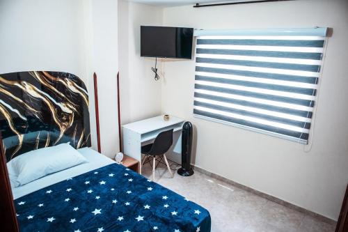 a bedroom with a bed and a window and a desk at EquiNox Central House Bucaramanga in Bucaramanga