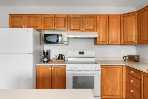 a kitchen with wooden cabinets and a white refrigerator at Lovely 1 BR APT in Moncton
