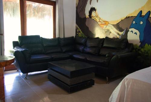 a living room with a black leather couch and a painting at Hostal Sierra Quindío in El Fénix