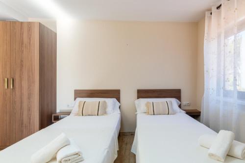 two beds in a room with white sheets and towels at Casa Navajas in Jérica