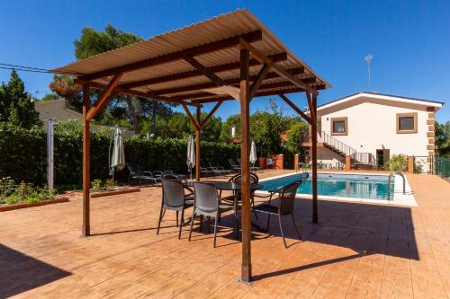 a wooden pavilion with a table and chairs next to a pool at Casa Navajas in Jérica