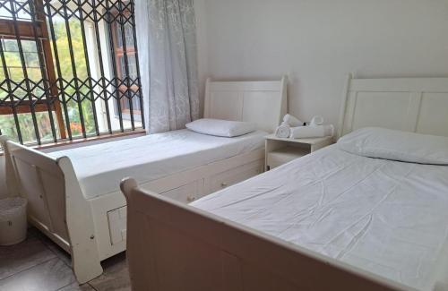 two beds in a room with a window at Home in Beacon Bay in East London