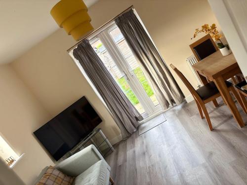 a living room with a large window and a television at Quiet Yellow Rest House Sleeps 7 in Swindon
