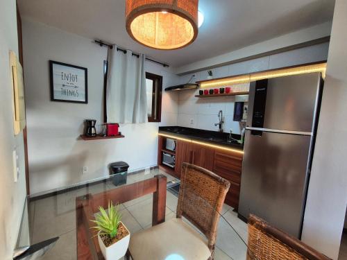a kitchen with a table and a stainless steel refrigerator at Solar de Pipa Prime - Frente piscina in Pipa