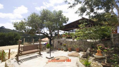 a park bench in a garden with potted plants at Chale em Serra Negra vista para montanha e lareira in Bezerros