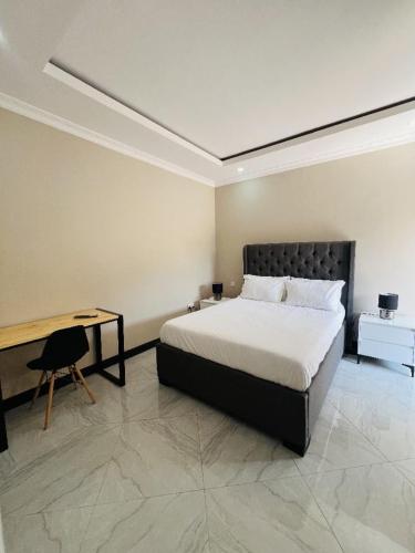 Un dormitorio con una cama, una mesa y un escritorio. en Palms & Pebbles Lodge, en Lilongwe