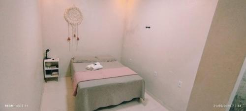 une petite chambre avec un petit lit aux draps roses dans l'établissement Casa com quartos compartilhados, à Belém
