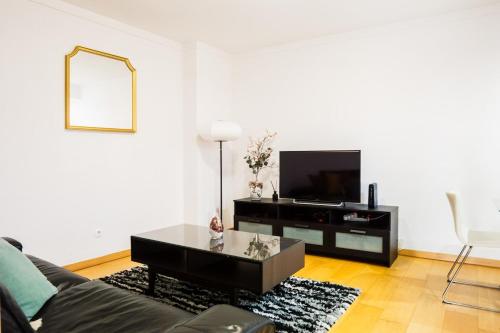 a living room with a couch and a tv at Charmoso Mirante in Lisbon