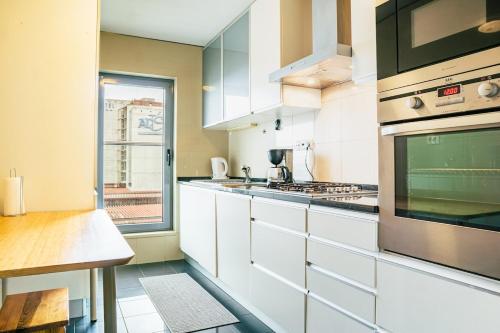 a large kitchen with white cabinets and a window at Charmoso Mirante in Lisbon