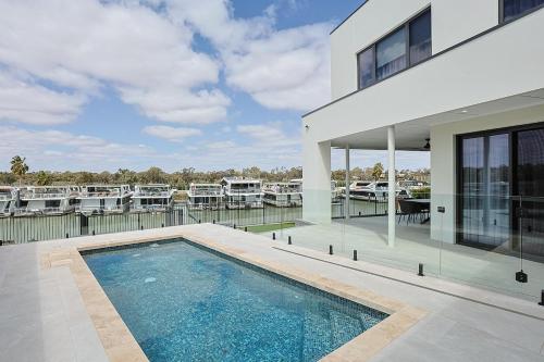 a house with a swimming pool next to a marina at Miles on the Murray in Mildura